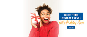 happy african american woman wearing red sweater and holding up christmas gift